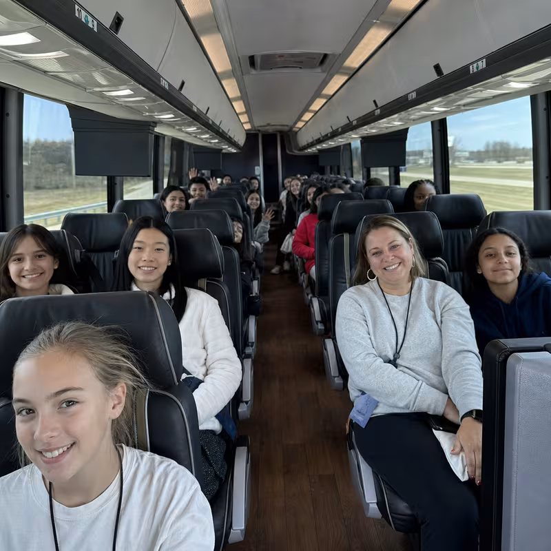 Group boarding a white charter bus for School Transportation transportation in Freemont